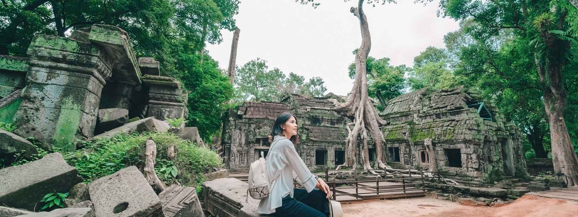 Young-female-tourist-wearing-a-hat-with-backpack-is-posing-at-Ta-Prohm-Temple